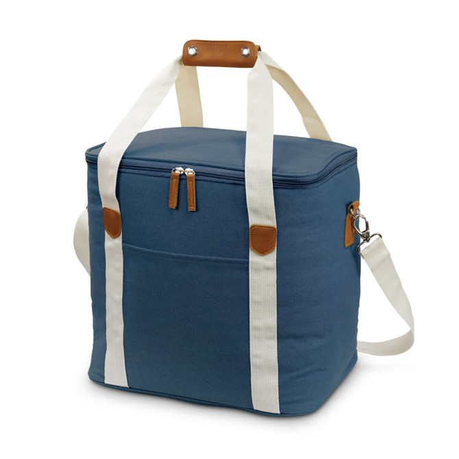 A canvas cooler bag in navy blue with cream straps and a brown leather handle, featuring a zippered top and front pocket.