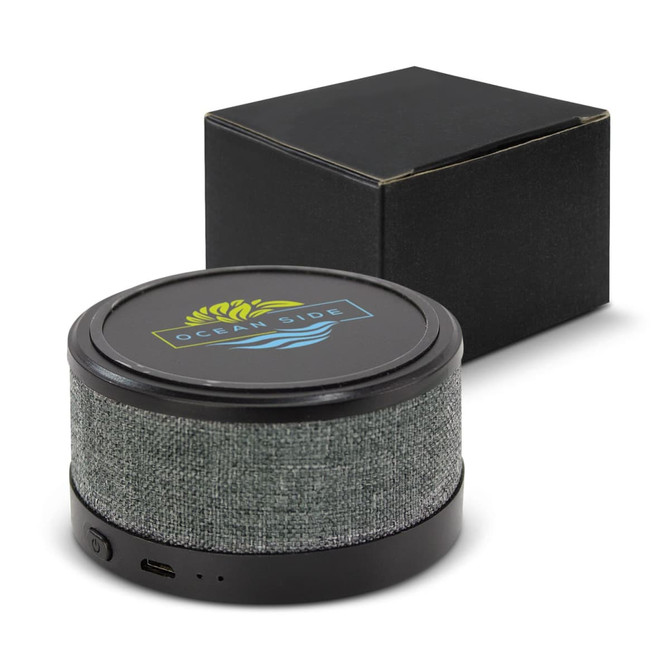 A wireless speaker with a grey fabric finish, featuring a round shape and a black base, alongside a black box.