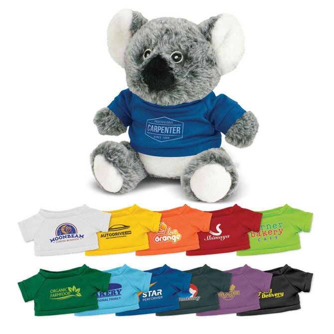 A koala plush toy with grey fur and white accents, wearing a blue shirt, displayed with various coloured shirts below.