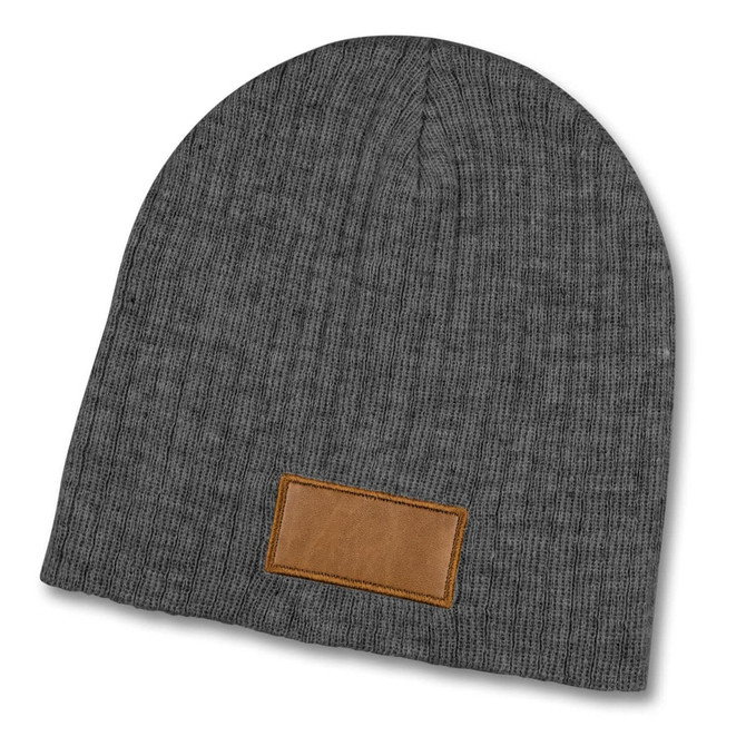 A grey cable knit beanie featuring a textured patch, designed for warmth and style.