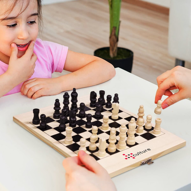 A compact travel chess set with wooden pieces in black and cream, displayed on a folding board.