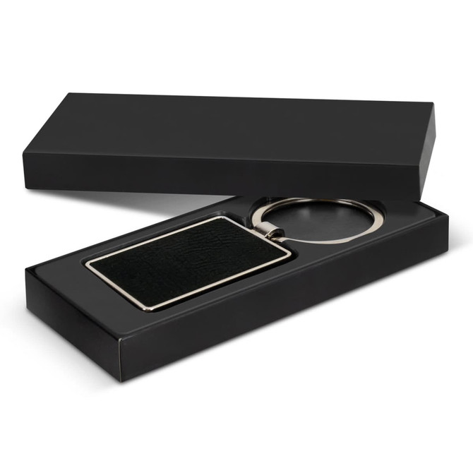 A rectangular black key ring with a metallic finish, presented in a sleek black box.