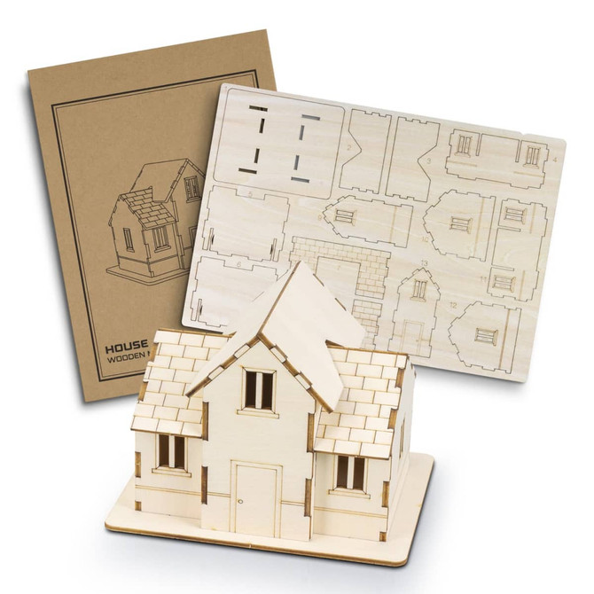 A wooden model of a house in natural wood colour, displayed with a laser-cut assembly sheet and a packaging design.