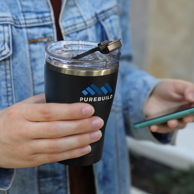 A drink bottle featuring a black exterior and a transparent lid, held by a person with a denim jacket. It has a logo.