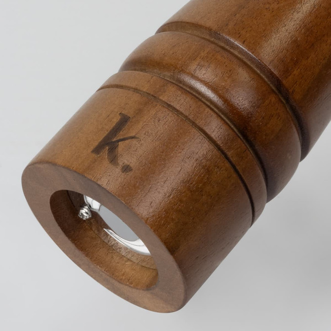 A wooden pepper mill with a smooth finish, featuring a circular base and a logo engraved on the side.