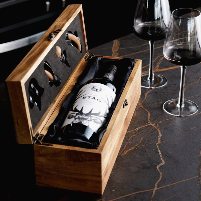 A wooden wine box set containing a wine bottle and wine glasses, set against a marble countertop.