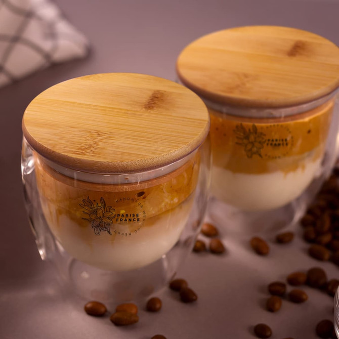 A drinkware set featuring two double-walled glass mugs with bamboo lids, showcasing layers of coffee and cream.