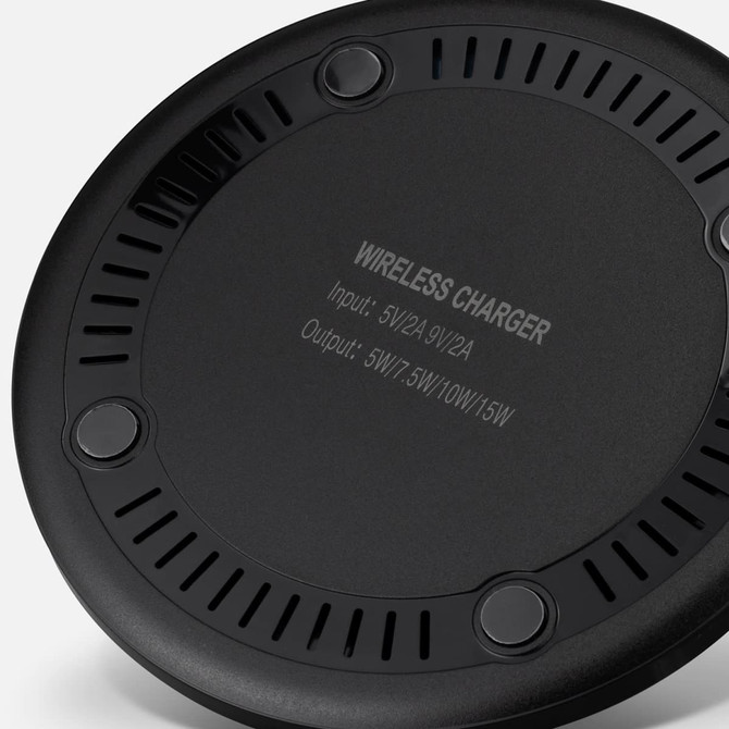A wireless charger in black with circular design and ventilation holes, featuring a branding logo on the underside.