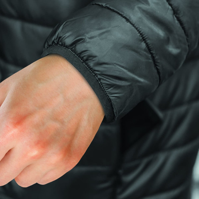 A close-up of the black cuff of a puffer jacket, featuring a smooth, elastic finish for snug fit.