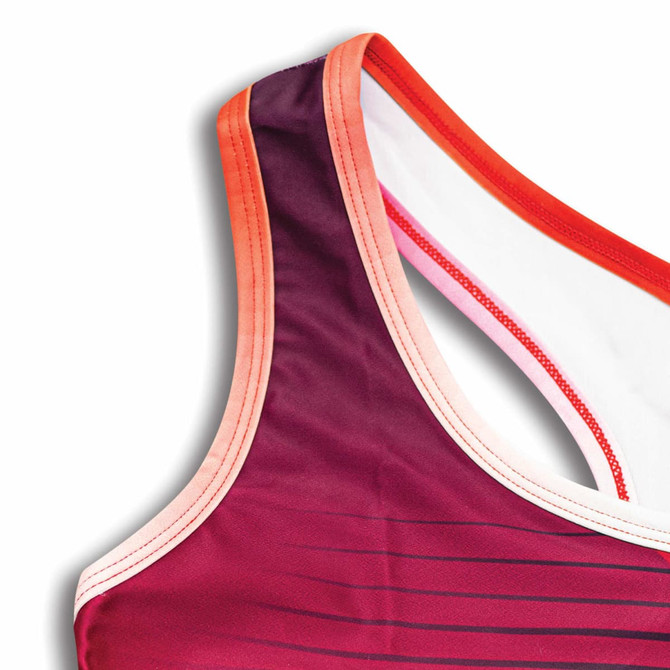 A custom women's athletics crop top in shades of purple and red with a contrasting trim and a branding logo.