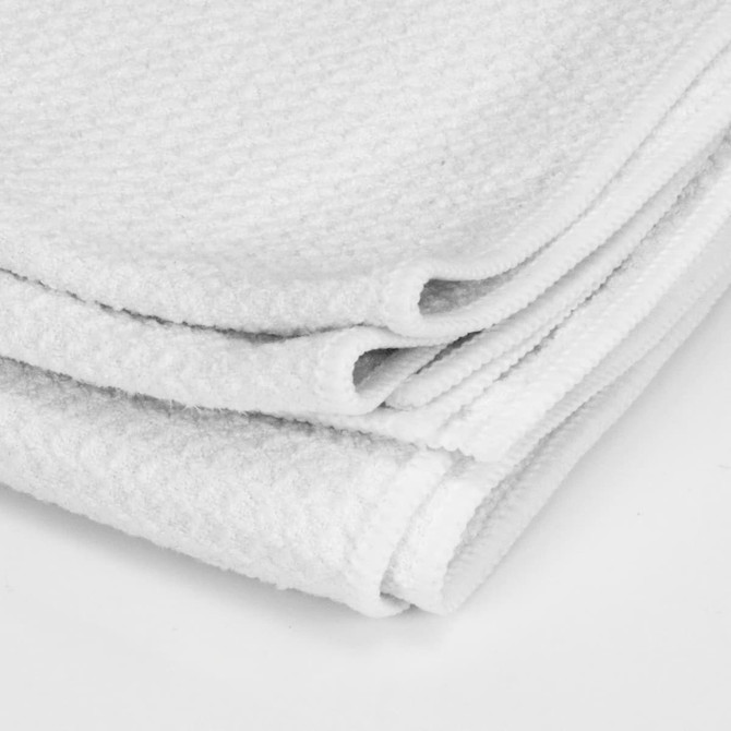 A white sand-free towel folded neatly, featuring a textured surface and stitched edges. It includes a logo.