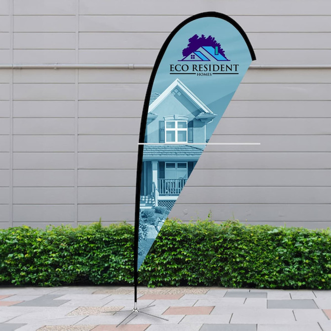 A tear drop flag kit featuring a black pole and a blue display. It includes a logo and stands on a pavement near greenery.