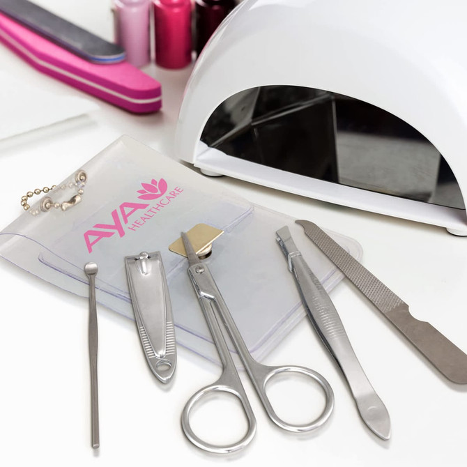 A vinyl manicure set with silver tools in a clear pouch, alongside a white nail lamp and pink nail files.