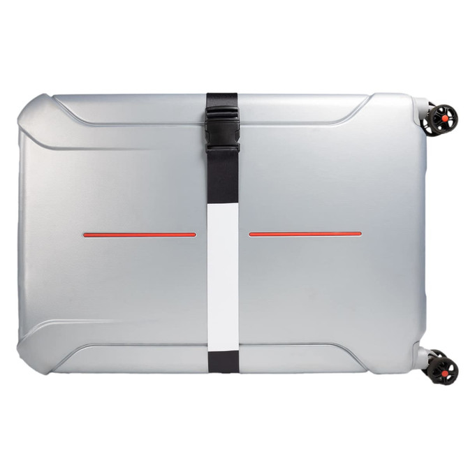 A luggage strap secures a silver suitcase, featuring a minimalistic design with a central white stripe and red accents.
