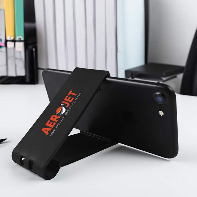 A black phone stand with a logo, positioned upright on a desk beside office supplies.