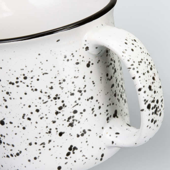 A ceramic mug with a speckled white design and a black rim, featuring a sturdy handle.