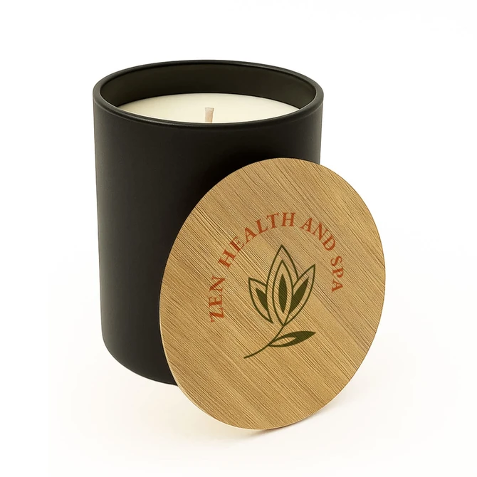 A large black glass candle with a wooden lid featuring a logo. The candle is cream-coloured inside.