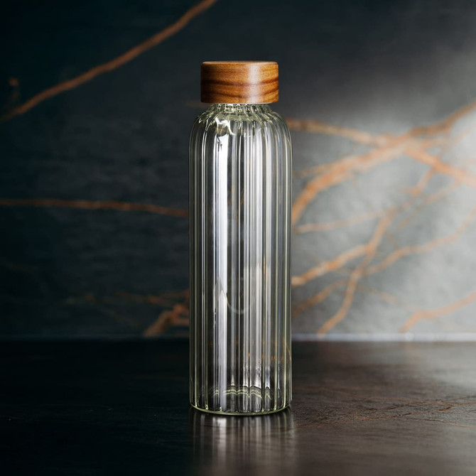 A drink bottle with a ribbed glass body and a wooden cap, featuring a clear colour against a textured background.