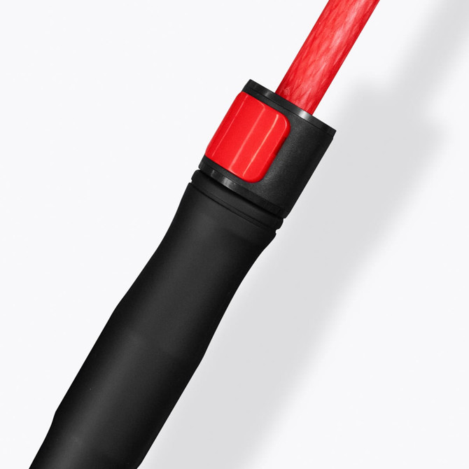 A close-up of a black and red handle of a Monsoon Umbrella, featuring a textured grip and a branding logo.