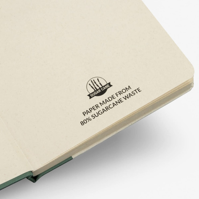 A beige notebook made from 80% sugarcane waste, featuring a branded logo on the cover.