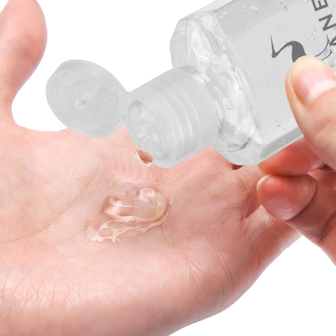 A clear hand sanitiser gel being dispensed from a 60ml bottle onto a palm. The bottle features a flip-top lid.