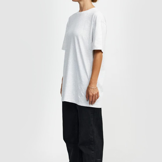 A light grey t-shirt with a relaxed fit, featuring short sleeves, displayed on a model alongside black trousers.