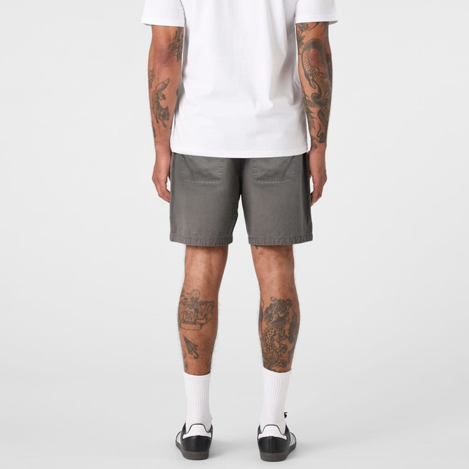 A pair of grey shorts viewed from the back, featuring pockets and a logo. The wearer has visible tattoos.