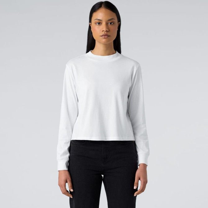 A white long sleeve tee, featuring a round neckline and a fitted design, worn with dark jeans.