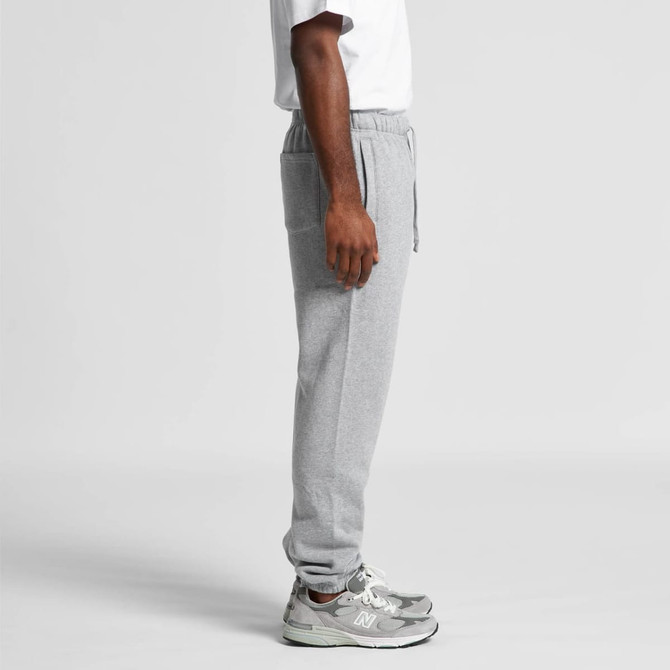 Grey track pants with an elastic waistband, side pockets, and a relaxed fit, paired with a white t-shirt and sneakers.