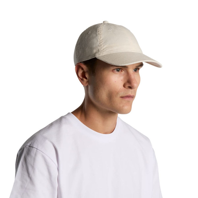 A light-coloured cap worn by a male model, featuring a simple design and a logo.
