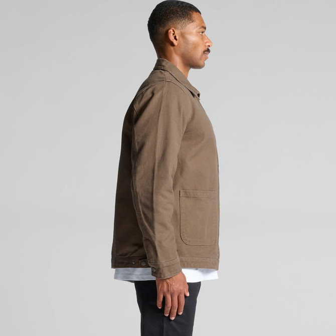 A man wears a brown heavy canvas jacket with a side view, featuring a pocket and a logo.