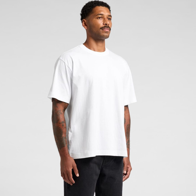 A white T-shirt featuring a relaxed fit, worn by a model with tattoos, standing against a plain background.