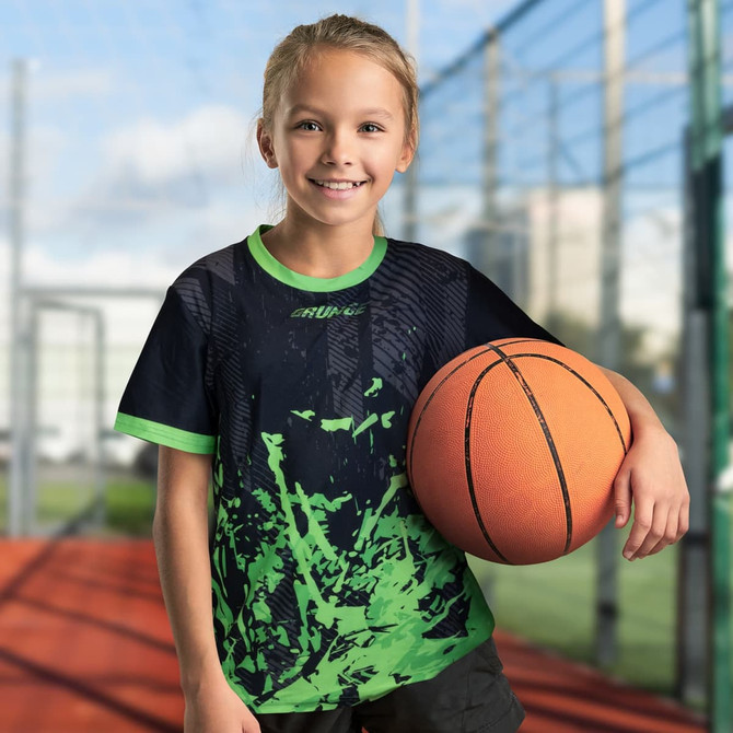 A custom kids sports T-shirt in black and green, featuring a logo, worn by a child holding a basketball.
