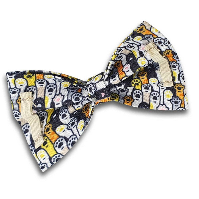 A pet bow tie featuring a colourful pattern of ghosts and paw prints on a dark background. It has a loop for attachment.