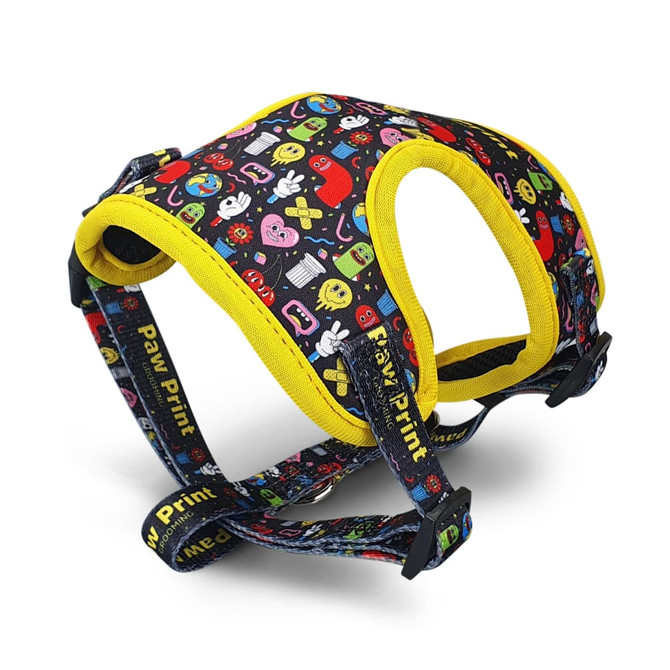 A pet harness featuring a black background with colourful patterns and yellow accents. It has a logo and adjustable straps.
