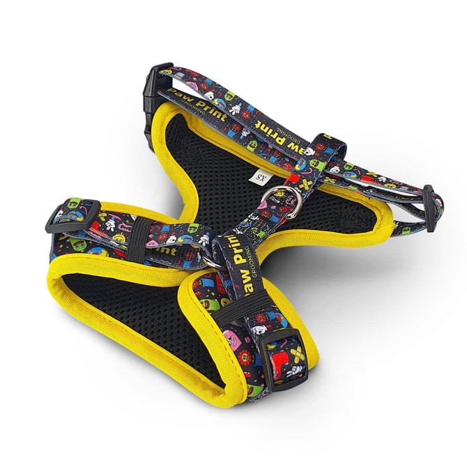 A pet harness in multicoloured patterns with a black mesh design and yellow trim. It features adjustable straps and a branding logo.