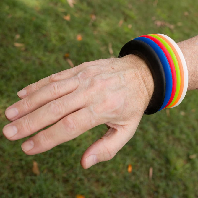 A hand with several colorful silicone wristbands in multiple colors, including black, red, yellow, blue, and green.