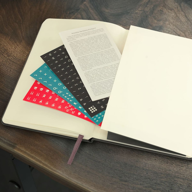 A Moleskine 2026 Weekly Planner with black covers, featuring blank pages and decorative inserts in various colours.