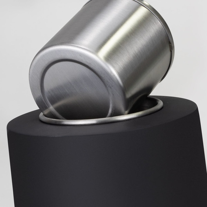 A sleek black waste bin with a brushed stainless steel lid partially tilted into the bin.