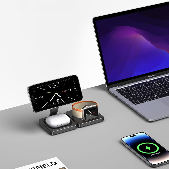 A sleek, black wireless charger for phones, AirPods, and smartwatches next to a laptop, featuring a modern design.