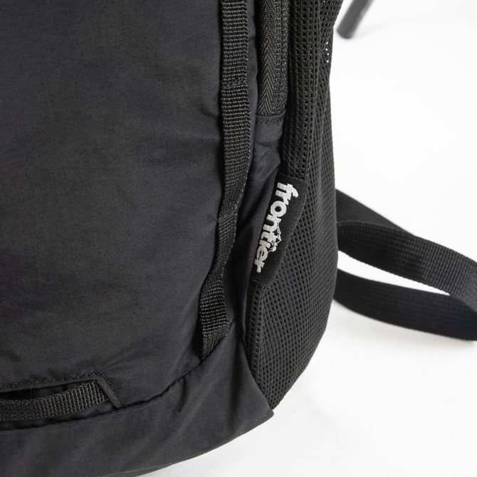A black daypack with mesh detailing and a logo on the side. The straps are partially visible.