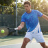 A sporty blue and white custom men's active t-shirt worn by a male tennis player on a court.