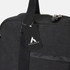 A black canvas duffle bag with a shoulder strap and a tag featuring a logo.