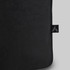 A black tote bag with a textured surface and a small branding tag.