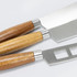 Three cheese knives with stainless steel blades and wooden handles in light and dark brown.