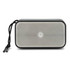 A rectangular grey bass speaker with a mesh front and a black cord attached for easy carrying.