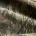 A close-up of fabric featuring a heavy faded camo pattern in green and brown tones.