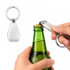 A silver keytag bottle opener being used to open a green glass bottle. The opener has a simple, sleek design.