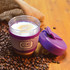 A reusable coffee cup with a purple silicone band and a matching lid, surrounded by coffee beans on a wooden surface.