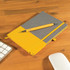 A Venture Bondi Notebook in gray and yellow with an Austin Pen resting on top, placed on a wooden desk.